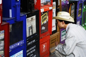 Someone reading headlines in news boxes