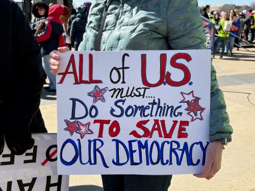Protest sign: All of us must do something to save our democracy.