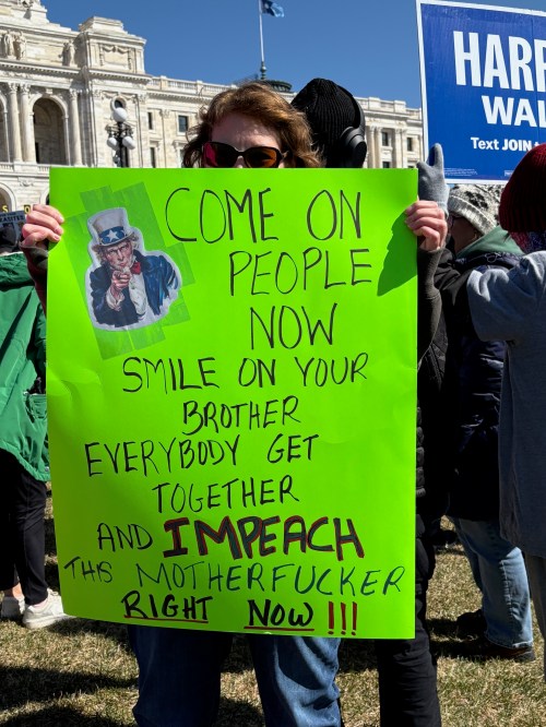Protest sign: Come on people now, smile on your brother. Everybody get together and impeach the motherfucker right now.